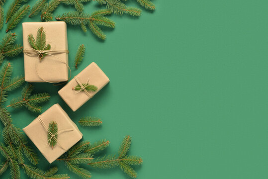Gift boxes with pine branches on green background.
