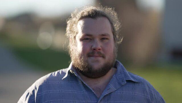 Portrait of a young chubby young man standing outdoors looking at camera. Close up overweight male person face in 20s