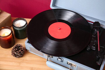 Vintage record player, burning candles and cone on wooden table, closeup