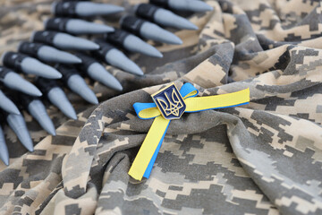 Ukrainian symbol and a machine gun belt on the camouflage uniform of a Ukrainian soldier. The...