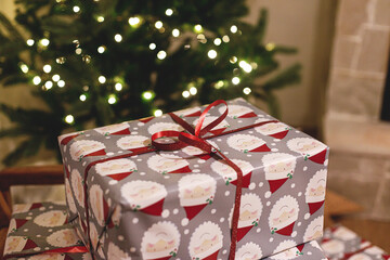 Merry Christmas! Stylish wrapped christmas gifts on arm chair against christmas tree with festive...