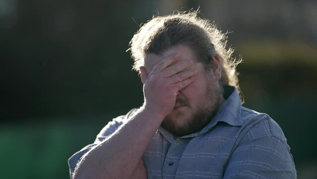 Worried young man standing outdoors with preoccupied expression. Frustrated anxious emotion of a chubby male caucasian person having panic attack