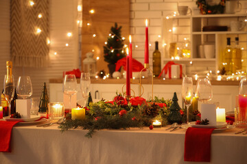 Festive table setting with Christmas decorations and glowing lights in kitchen at evening