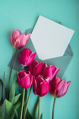 Empty white envelope copy space for your text or design with beautiful pink tulip bouquet on green...