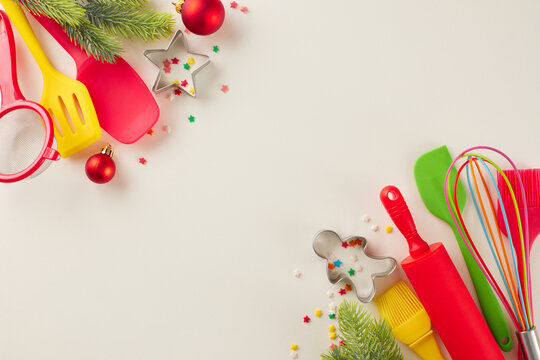 Idea of preparing Christmas confections. Top view photo of candies, xmas balls, pastry tools, baking molds, fir twigs, stars confetti on light beige background with promo zone