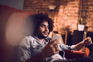 Carefree young man with eyes closed listening to music at home