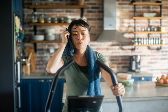 Young Asian woman on a exercise bike at home