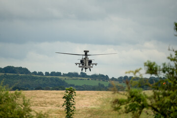 Fototapeta na wymiar British army Boeing Apache Attack helicopter gunship AH64E (AH-64E Army Air606) hovering low over summer countryside