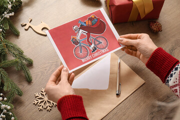 Mature woman with greeting card for Christmas celebration on table, closeup