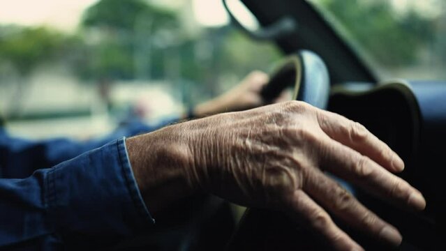 Close up hands holding steering driving in city. One senior male caucasian driver inside moving vehicle signaling turn