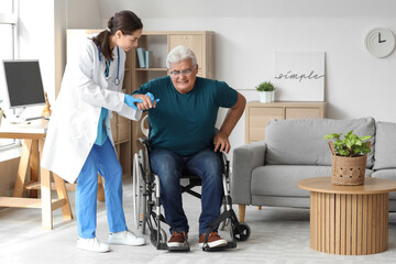 Fototapeta na wymiar Nurse helping senior man to stand up from wheelchair at home
