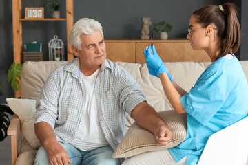 Obraz premium Nurse taking blood from senior man at home