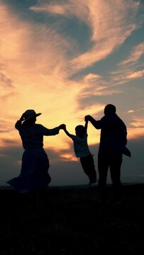 Silhouette of a happy family at sunset. Vertical video