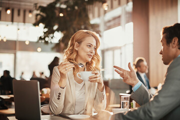 Young man and woman in suit drinking coffee in cafe