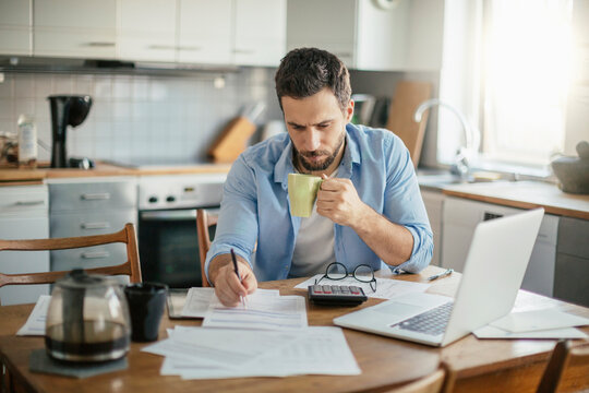 Serious young man reading bill document at home