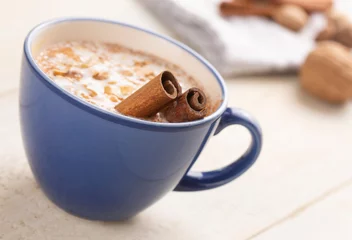 Fotobehang Blue cup of salep milky hot drink of Turkey with cinnamon powder and sticks healthy spice and autumn winter içeceği on white rustic vintage wooden table. © Esin Deniz