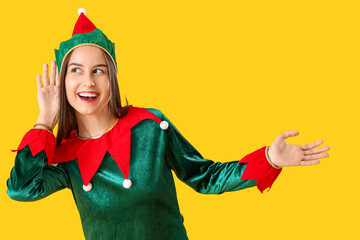 Beautiful young woman in elf's costume on yellow background