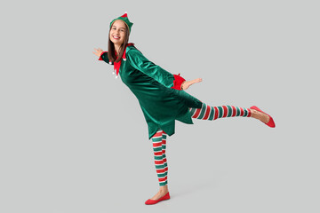 Beautiful young woman in elf's costume on grey background