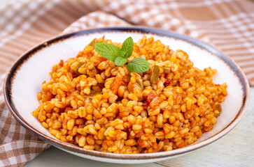 Traditional turkish bulgur pilaf with tomato sause in plate (Turkish name; meyhane pilavi)