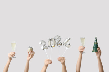 Female hands with figure 2024 made of balloons and glasses of champagne on white background - obrazy, fototapety, plakaty
