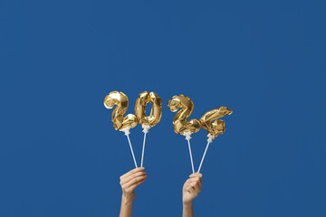 Female hands with figure 2024 made of balloons on blue background