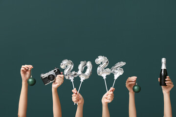 Female hands with champagne bottle, camera and figure 2024 made of balloons on green background