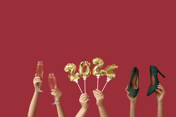 Female hands with high heel shoes, champagne glasses and figure 2024 made of balloons on red background