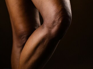 Fototapeta na wymiar Legs of middle aged black woman closeup on black background