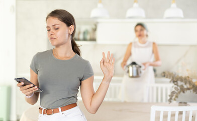 Woman argues with girl in kitchen, expressing her dissatisfaction and indignation