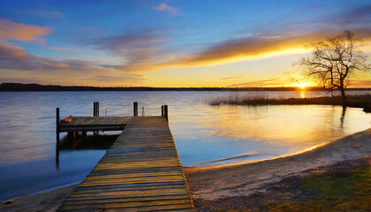 Fototapeta premium sunset over the beach with a dock by a lake