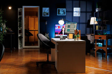 An empty newly opened workplace in a contemporary style is seen at night with desktop graphics...