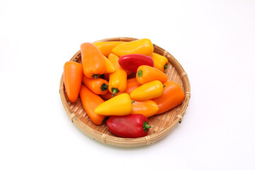 白背景の様々な色の笊にいれたカラーピーマン