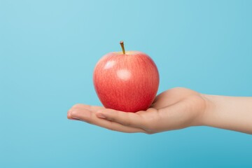 Handheld sweetness: a hand presenting a luscious red apple, a handheld ode to the sweetness of nature