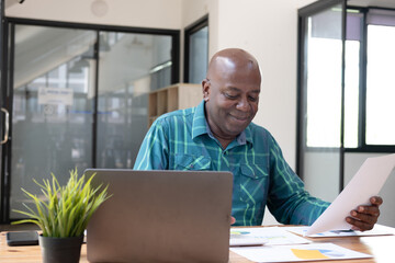 Fototapeta premium Young business man working at home with laptop and papers on desk