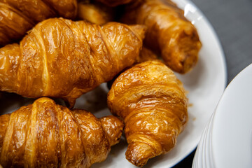 Freshly baked croissants in a white plate on a table