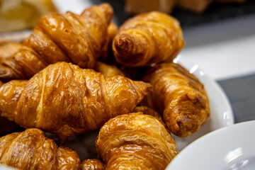 Freshly baked croissants in a white plate on a table