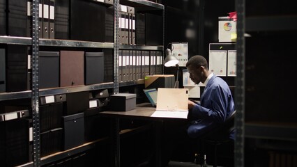 Male investigator digs deep into case, looks through evidence and skillfully analyzing data....