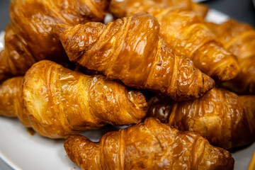 Freshly baked croissants in a white plate on a table