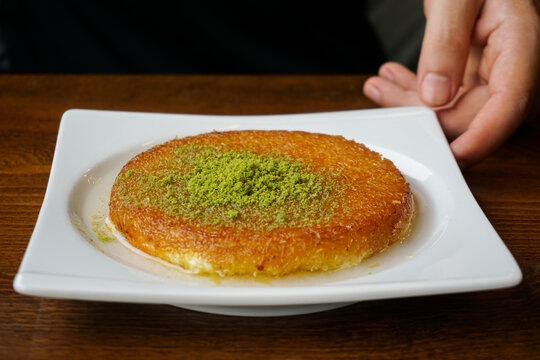 hand holding a plate with kunefe