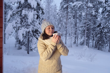 Fototapeta na wymiar happy mature woman 50 years old drink hot tea in winter forest, early evening in park among snow-covered trees, beautiful landscape, smiling happily, concept active lifestyle, enjoying winter nature