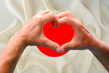 close-up of male hands in heart form against background of silk national flag of Japan, patriots of...