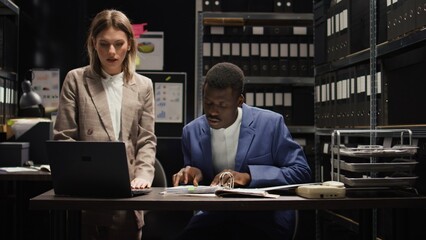 African american and caucasian police officers work together to solve crucial criminal case. Two...