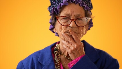 Closeup portrait of toothless funny elderly senior old woman with wrinkled skin looks at camera...