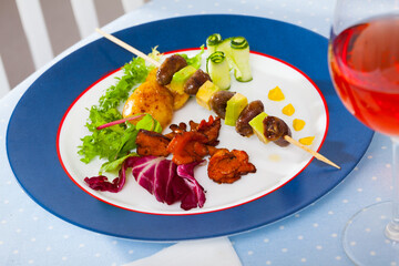 Plate of delicious fried chicken hearts on skewer with avocado, potatoes, roasted chanterelles and...