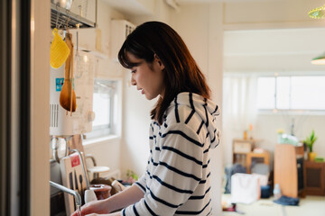 団地の台所で家事をする女性