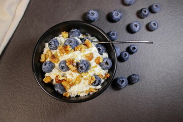 Cottage cheese with fresh blueberries in black bowl, hight protein dessert