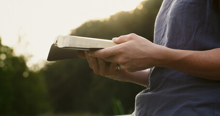 Woman reading the bible in a park. Christian faith and bible study
