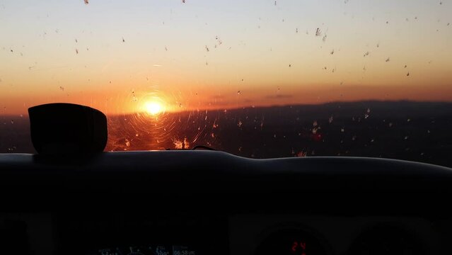 POV view from the cockpit of a small airplane flying into a vibrant sunset