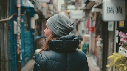 Caucasian woman walking Japanese streets, explore Tokyo downtown culture and architecture. Girl walking and exploring, tourist attraction, Japan tourism, Asian city life concept. Back view slow motion