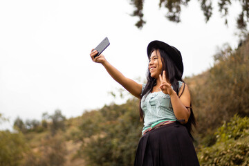 Foto de una feliz y bonita campesina caucásica con un sombrero hablando por un teléfono celular...